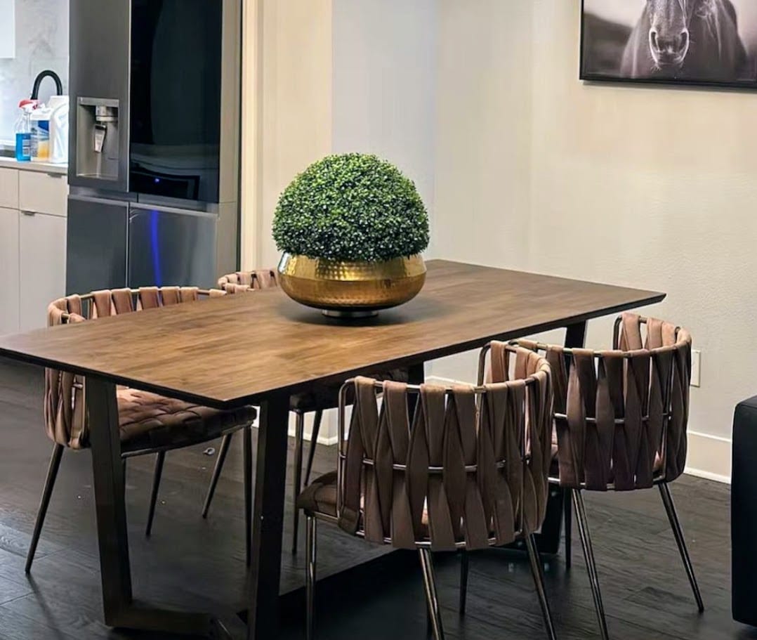 Dining table with chairs and a decorative plant in a modern interior setting.