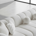 White textured sofa with decorative pillows on a light gray floor.