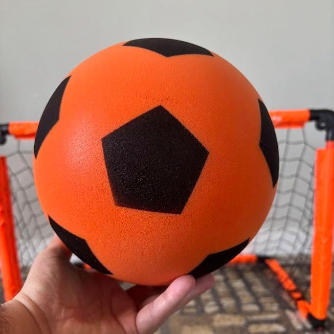 Orange and black soccer ball held in front of a small orange goalpost.