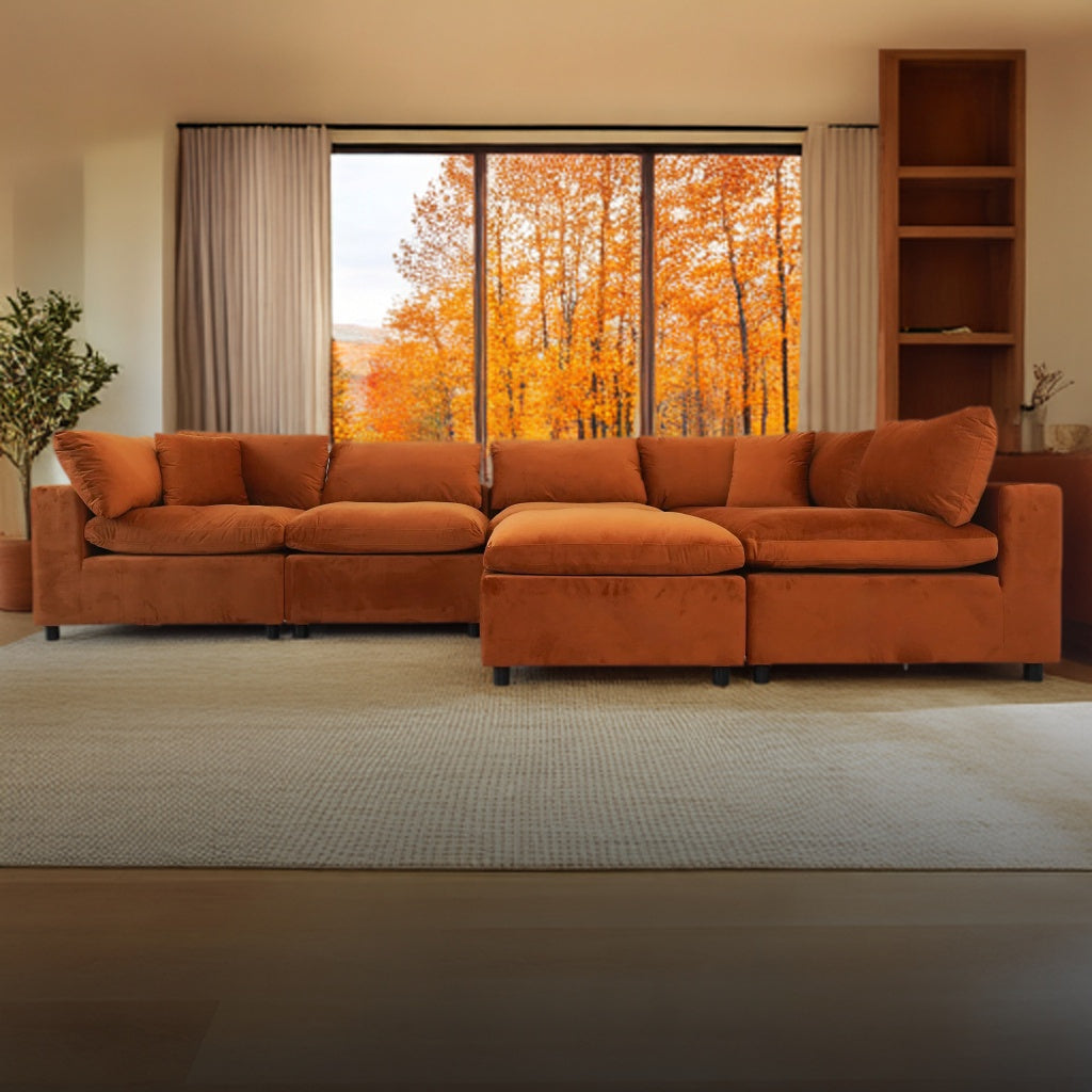 Orange sectional sofa in a living room with a window view of autumn trees.