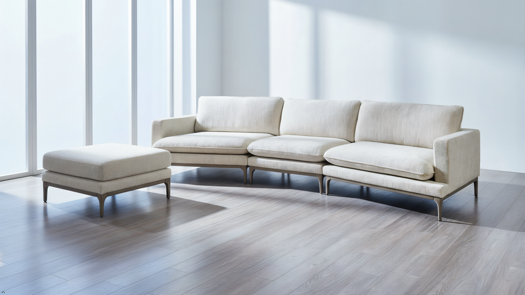 Beige sectional sofa with ottoman in a modern room with large windows.