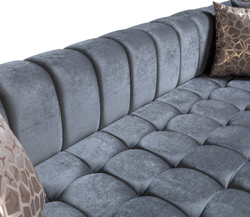 Gray tufted sofa with patterned cushions on a white background