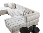 Beige sectional sofa with ottoman and two black round tables on a white background