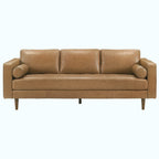 A three-seat leather sofa in a warm tan/camel color, featuring a tufted seat cushion, cylindrical armrests, and tapered wooden legs, shown against a plain white background.