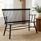 Black metal bench in a room with plants and a wooden side table.