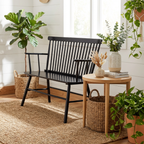Black bench in a room with plants and a wooden table