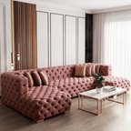 Pink tufted sofa in a modern living room with a coffee table and decorative items.