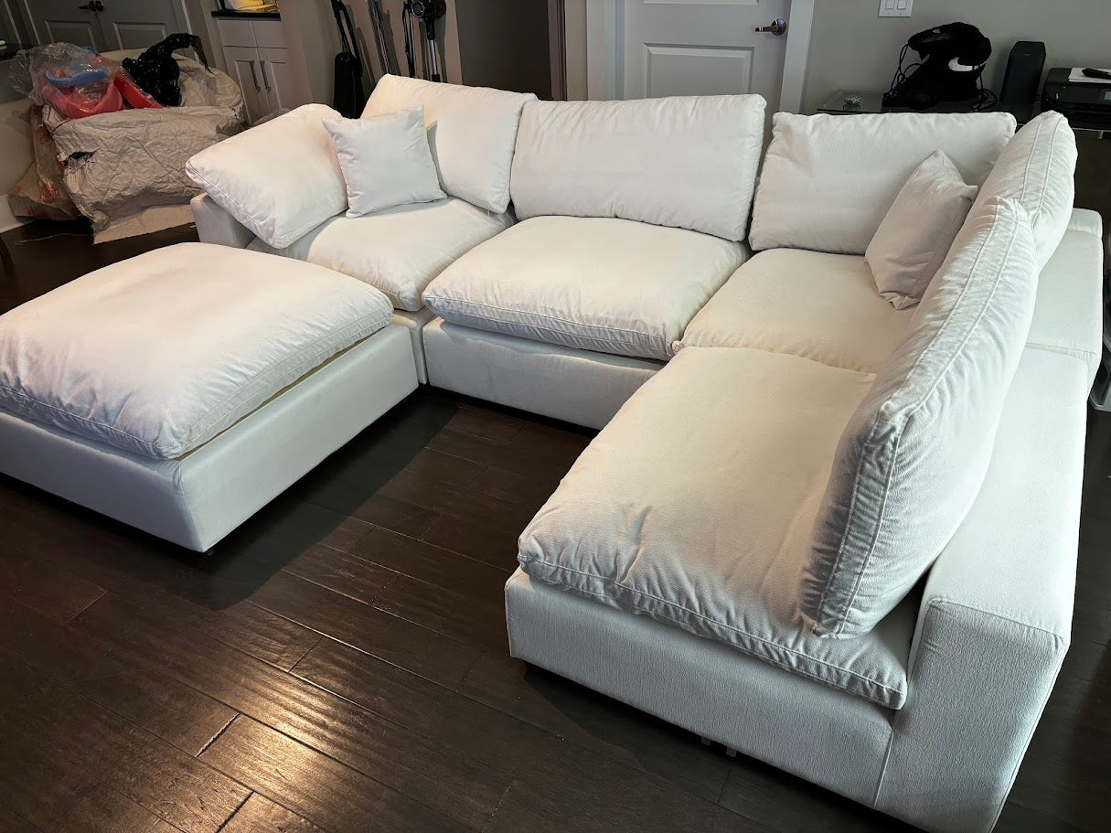 White sectional sofa in a living room setting with wooden flooring.