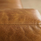 Close-up of brown leather surface with visible texture and seam.