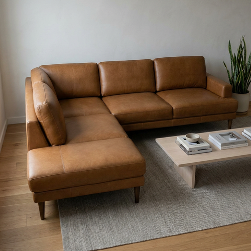 Brown leather sectional sofa in a living room with a coffee table and plant.