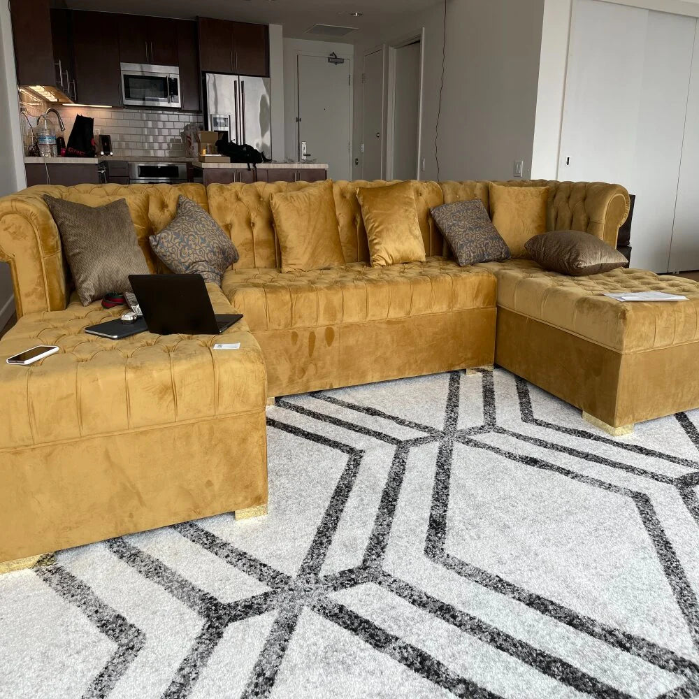 Mustard double chaise  u shaped chic velvet sectional sofa in a living room with a geometric patterned rug.