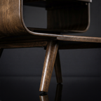 Close-up of a wooden chair leg on a dark reflective surface