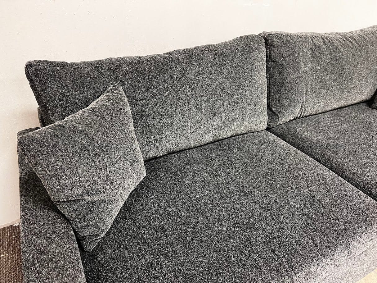 Gray sectional sofa with cushions on a light background 