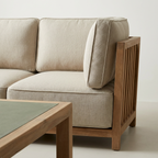 Beige sofa with wooden frame and a matching coffee table on a light background