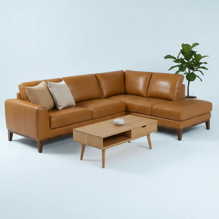 Brown leather sectional sofa with a wooden coffee table on a light blue background