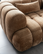 Brown textured sofa with cushions on a light gray floor.