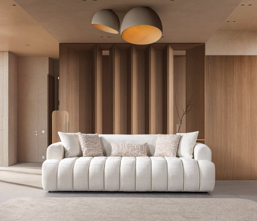White sofa with patterned cushions in a modern living room with wooden walls and ceiling lights.