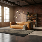 Brown leather sofa in a room with brick walls and large windows.