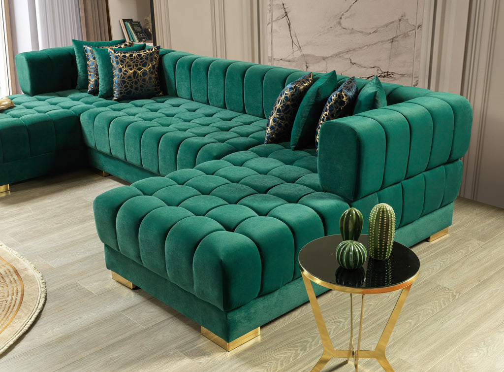 Green velvet sectional sofa with gold legs in a room setting.