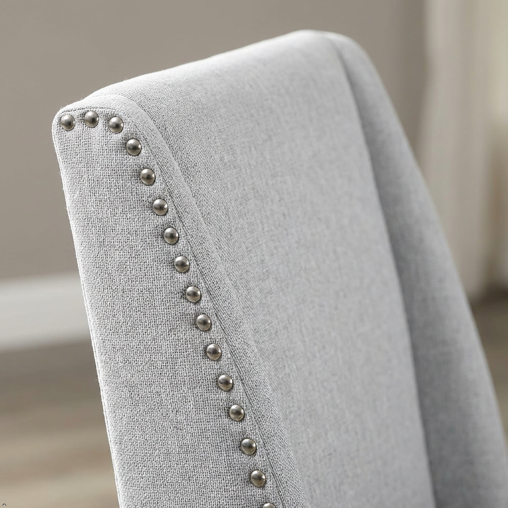 Gray upholstered chair with studded detailing on a neutral background