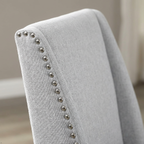 Gray upholstered chair with studded detailing on a neutral background