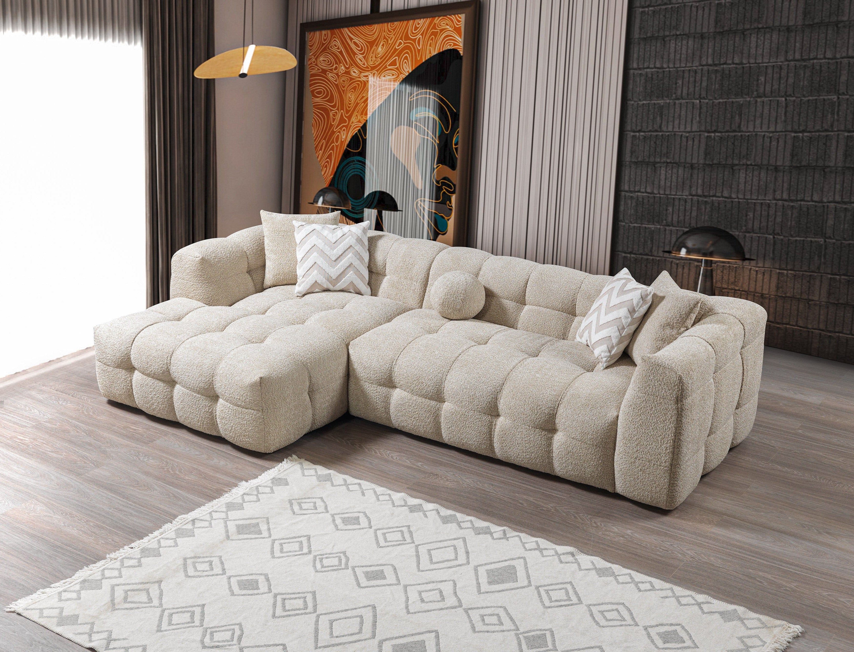 Beige sectional sofa in a living room with a patterned rug and abstract painting.