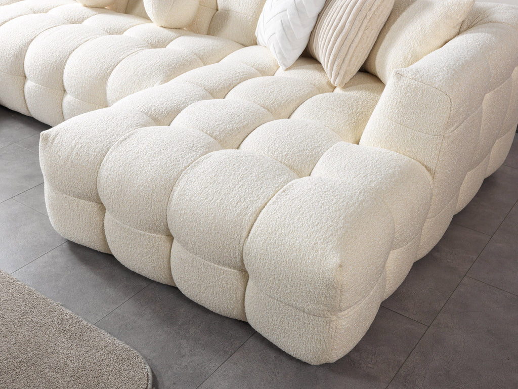 Close-up of a textured cream-colored sofa on a tiled floor.