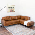 Brown leather sectional sofa in a living room with a colorful rug and wall art.