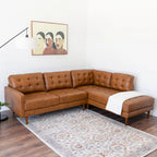 Brown leather sectional sofa in a living room with a colorful rug and wall art.