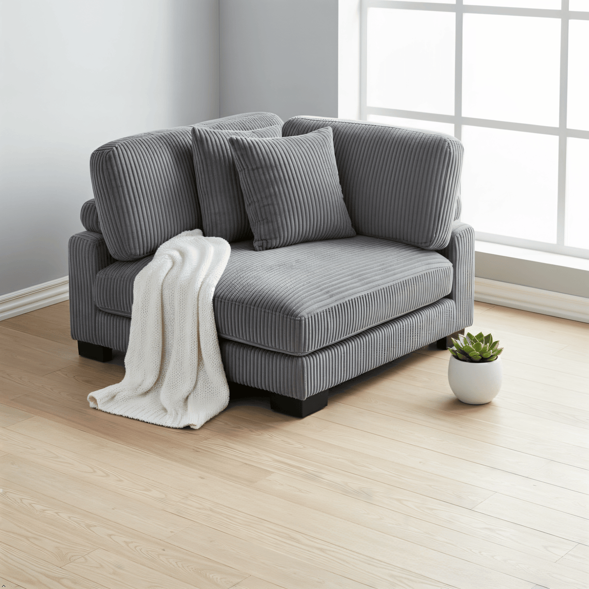 Gray sofa with a white blanket in a room with a window and plant