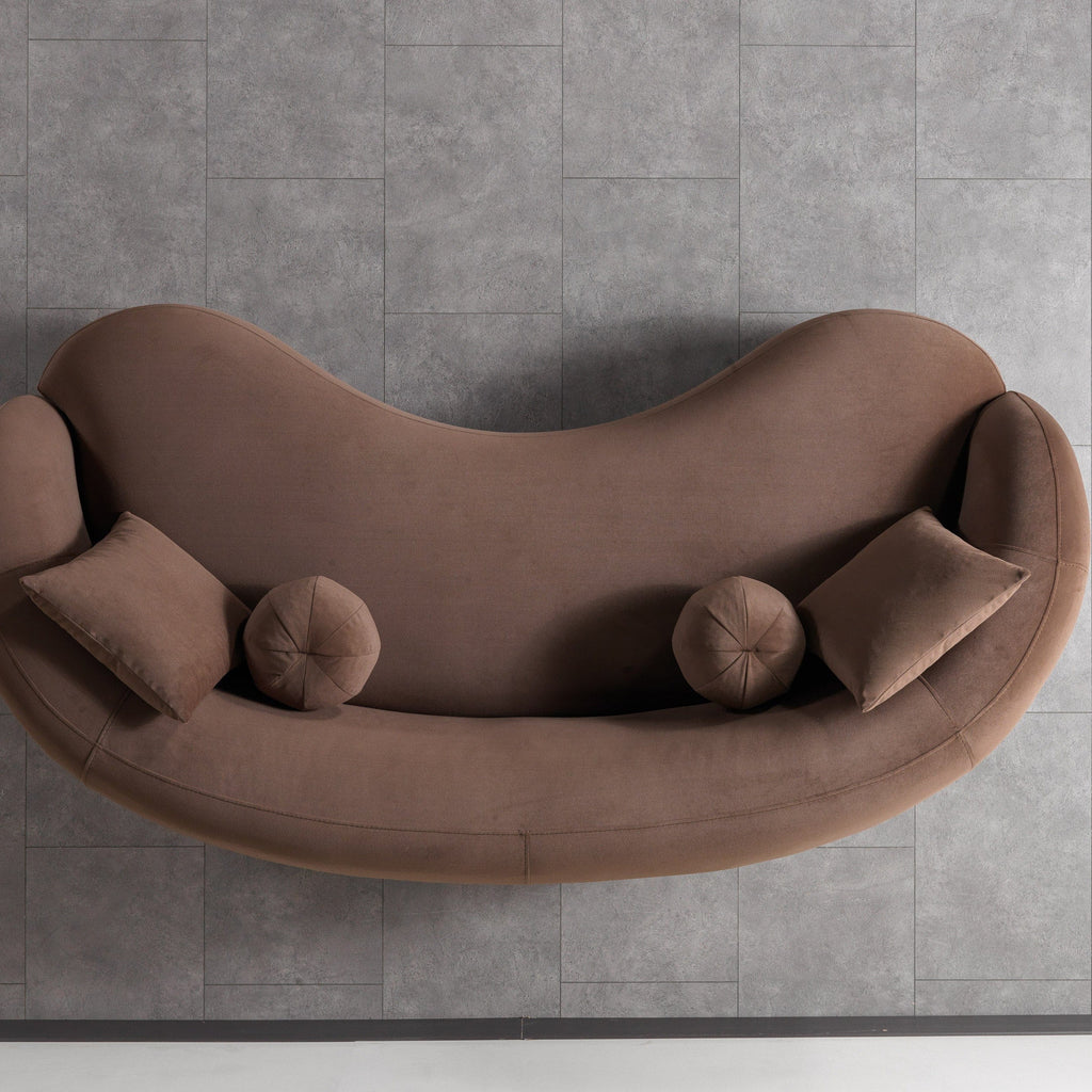 Brown curved sofa with cushions on a gray tiled floor