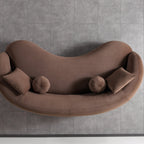 Brown curved sofa with cushions on a gray tiled floor