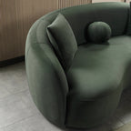 Green sofa with cushions in a room with wooden paneling.
