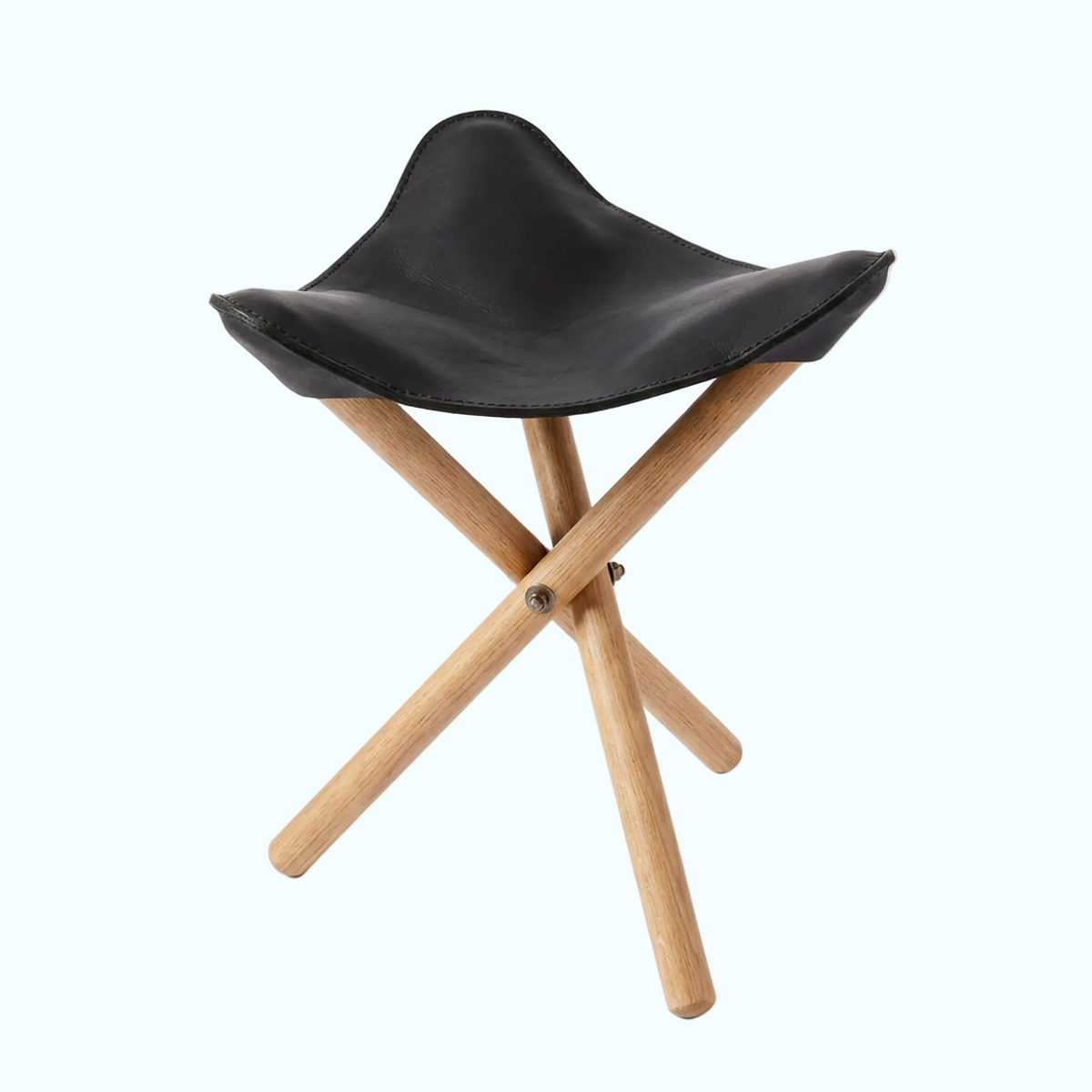 A modern folding stool with a black leather seat and light natural wood legs, shown on a clean white background.