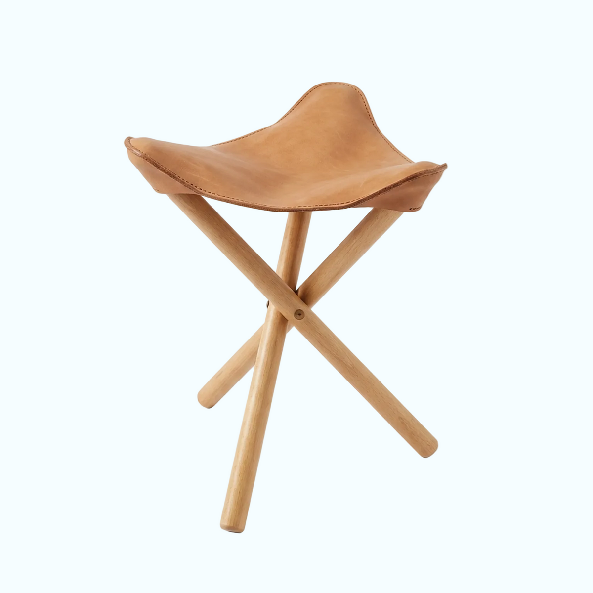 A compact folding stool with a light brown leather seat and natural wood legs, shown on a clean white background.