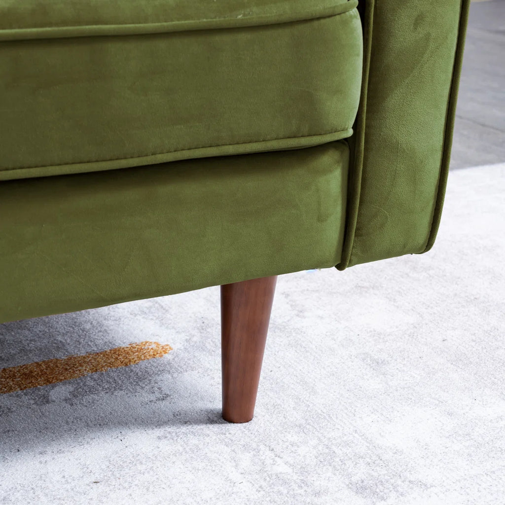 Close-up of an olive green upholstered chair or sofa leg with a tapered brown wooden leg, shown on a light gray floor.