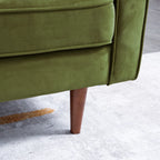 Close-up of an olive green upholstered chair or sofa leg with a tapered brown wooden leg, shown on a light gray floor.