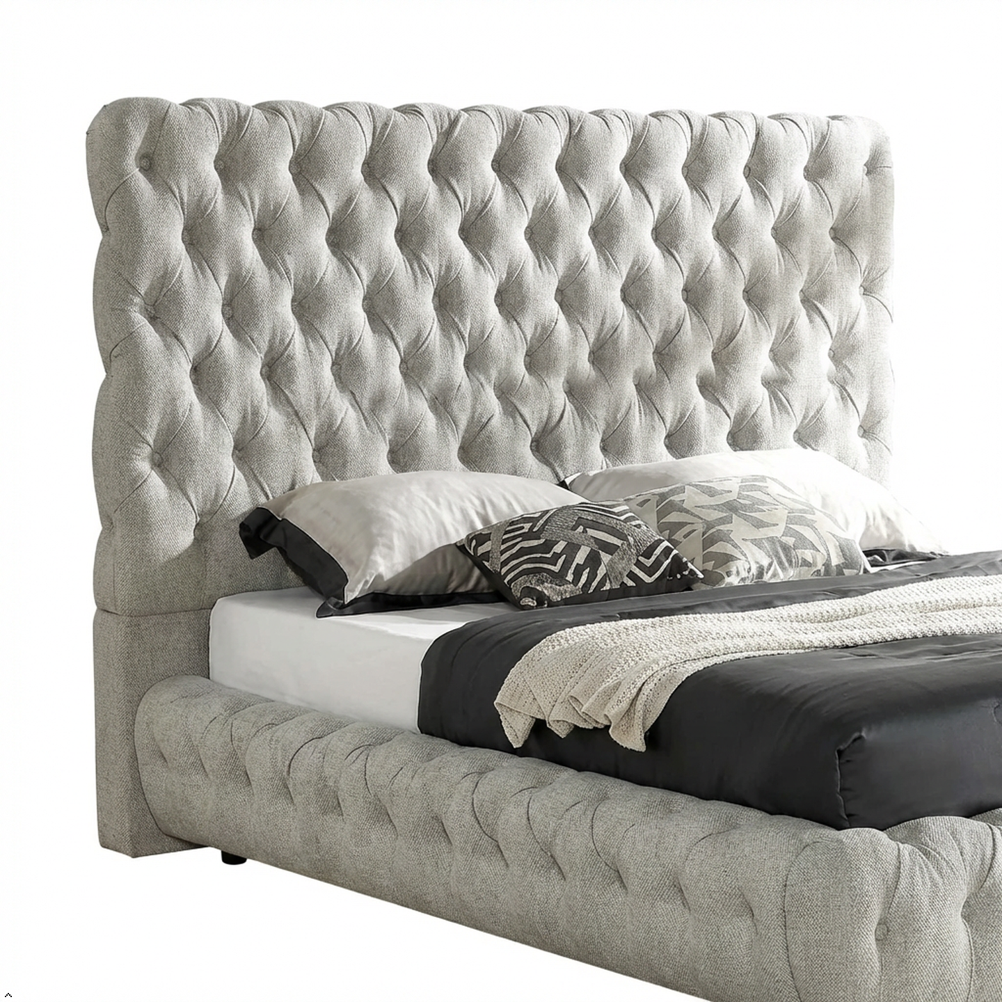 Gray tufted bed with white bedding and decorative pillows on a white background