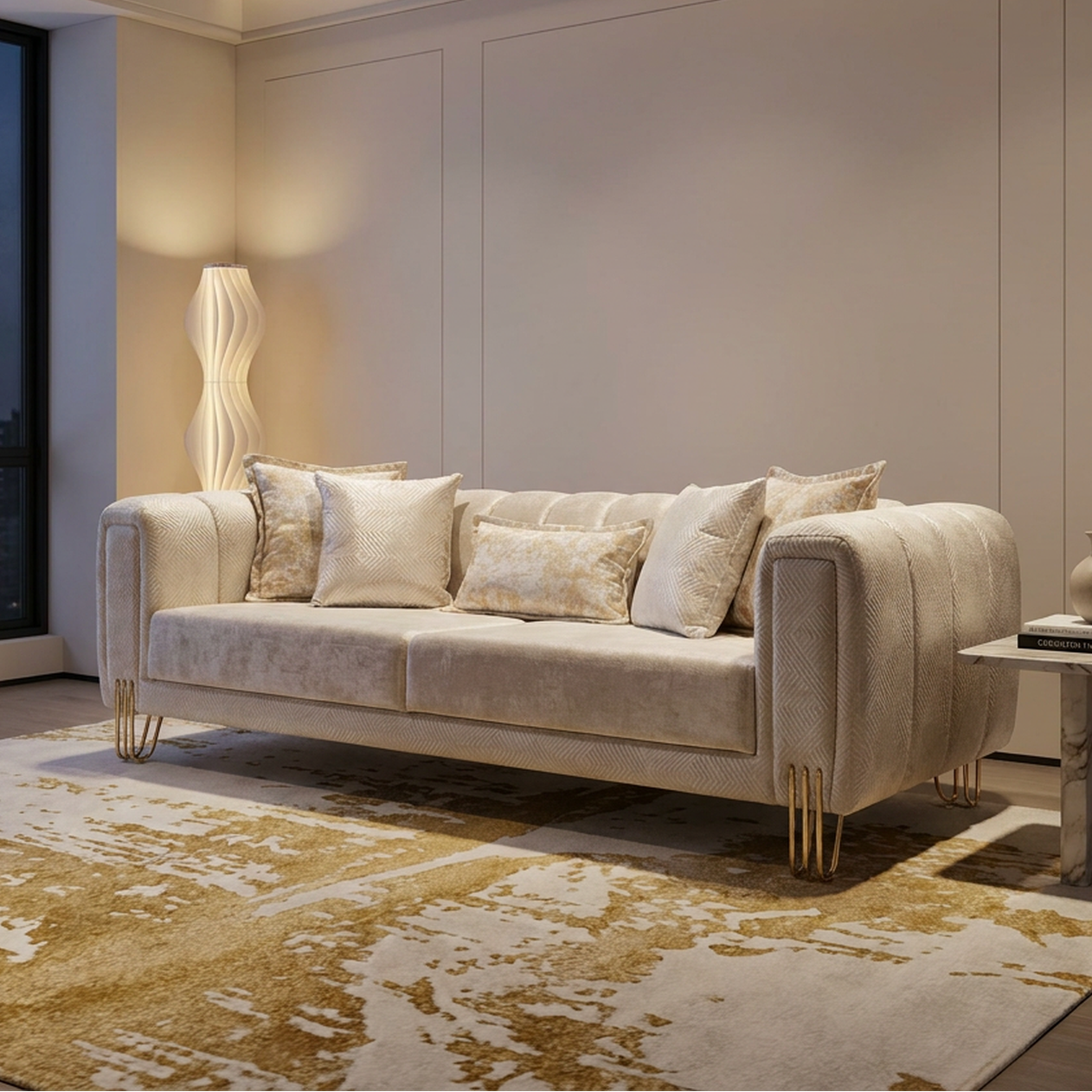 A modern beige velvet sofa with gold metal legs, styled in a luxury living room with a matching patterned rug, marble side table, and warm ambient lighting.