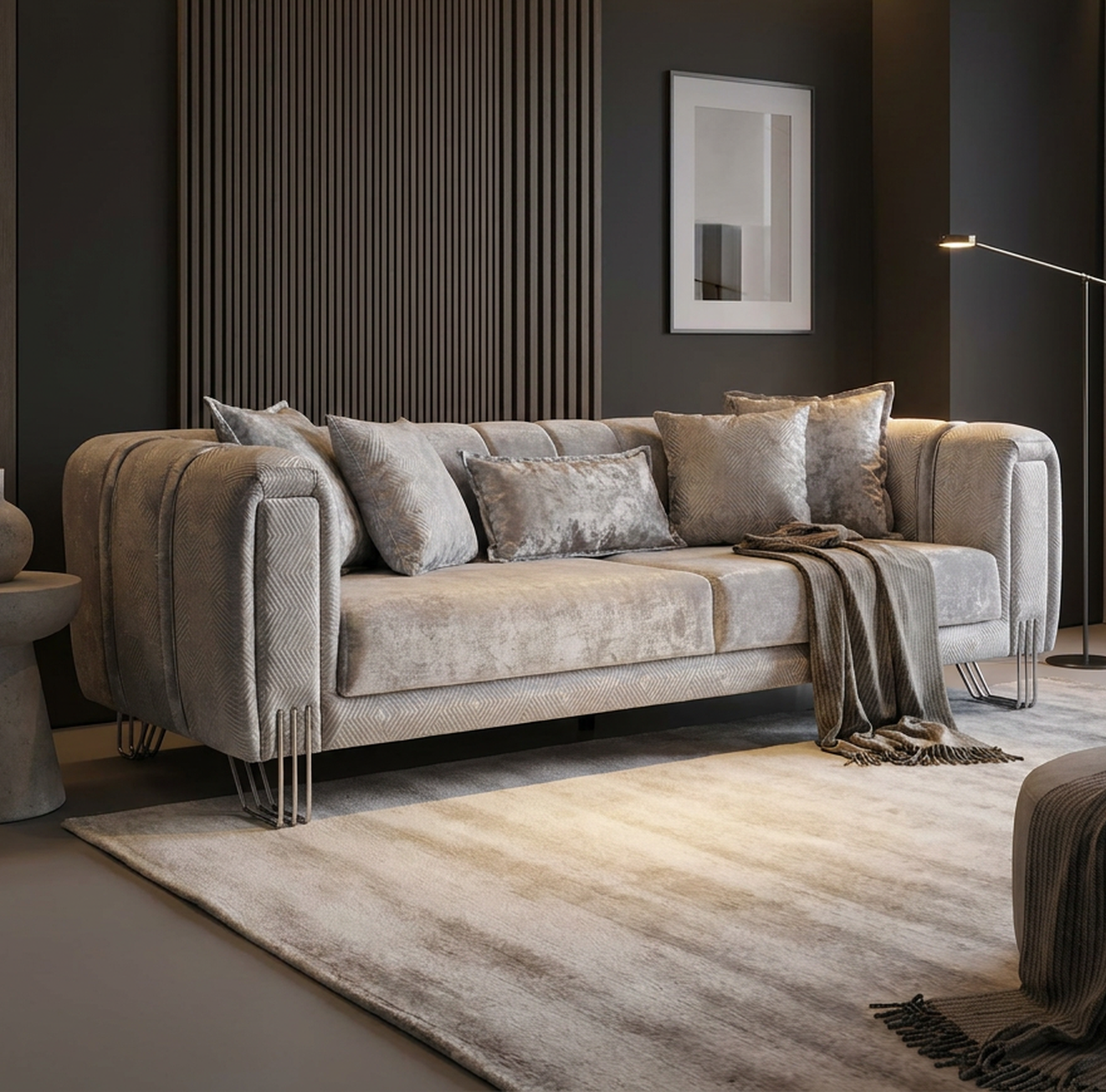 A modern gray velvet sofa with matching throw pillows and a draped knit blanket, set in a contemporary living room with a slatted wood accent wall, a side table, and a striped area rug.