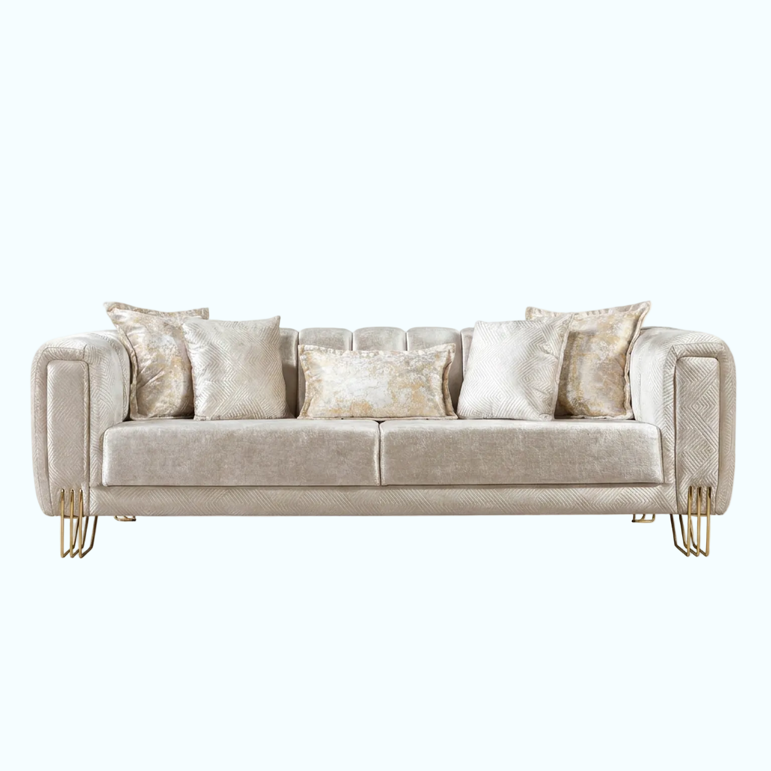 A modern three-seater sofa upholstered in a textured champagne beige fabric, styled with five matching throw pillows, including two with a shimmering gold pattern. The sofa features elegant curved arms and slim gold metal legs, set against a solid light blue background.