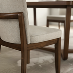 Close-up of a wooden chair with gray cushioned seat and backrest.