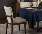 Dining room with a set table, chairs, and a bench against a dark wall with framed pictures.
