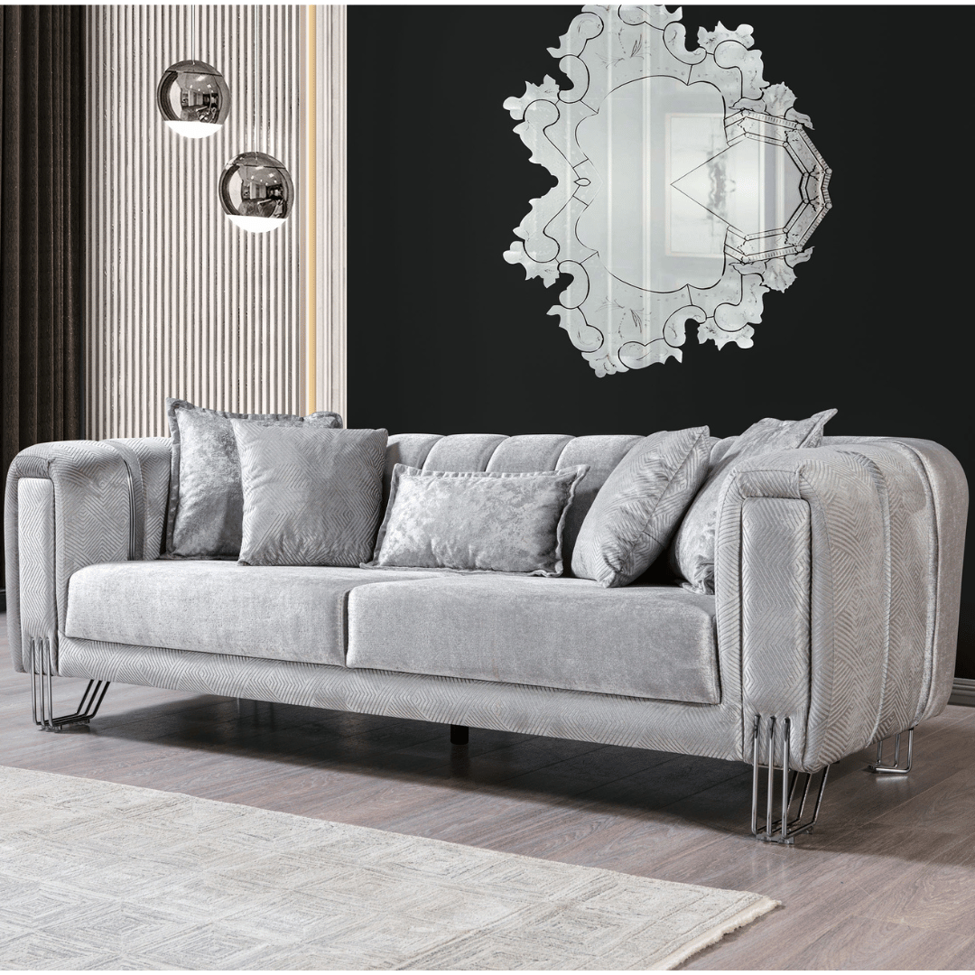 Silver sofa with decorative pillows in a room with a mirror on the wall.