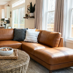 Brown leather sectional sofa in a living room with cushions and a wicker coffee table.