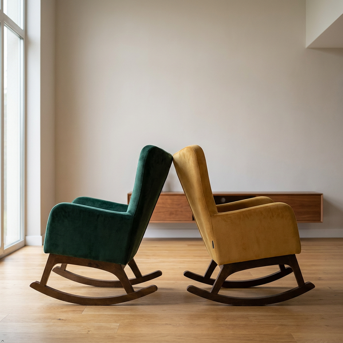 Two modern velvet rocking chairs in dark wood frames, one in deep teal green and the other in mustard yellow, placed on a light wood floor in a minimalist room.