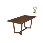 Wooden dining table in a modern living room setting with a dresser and lamp in the background.