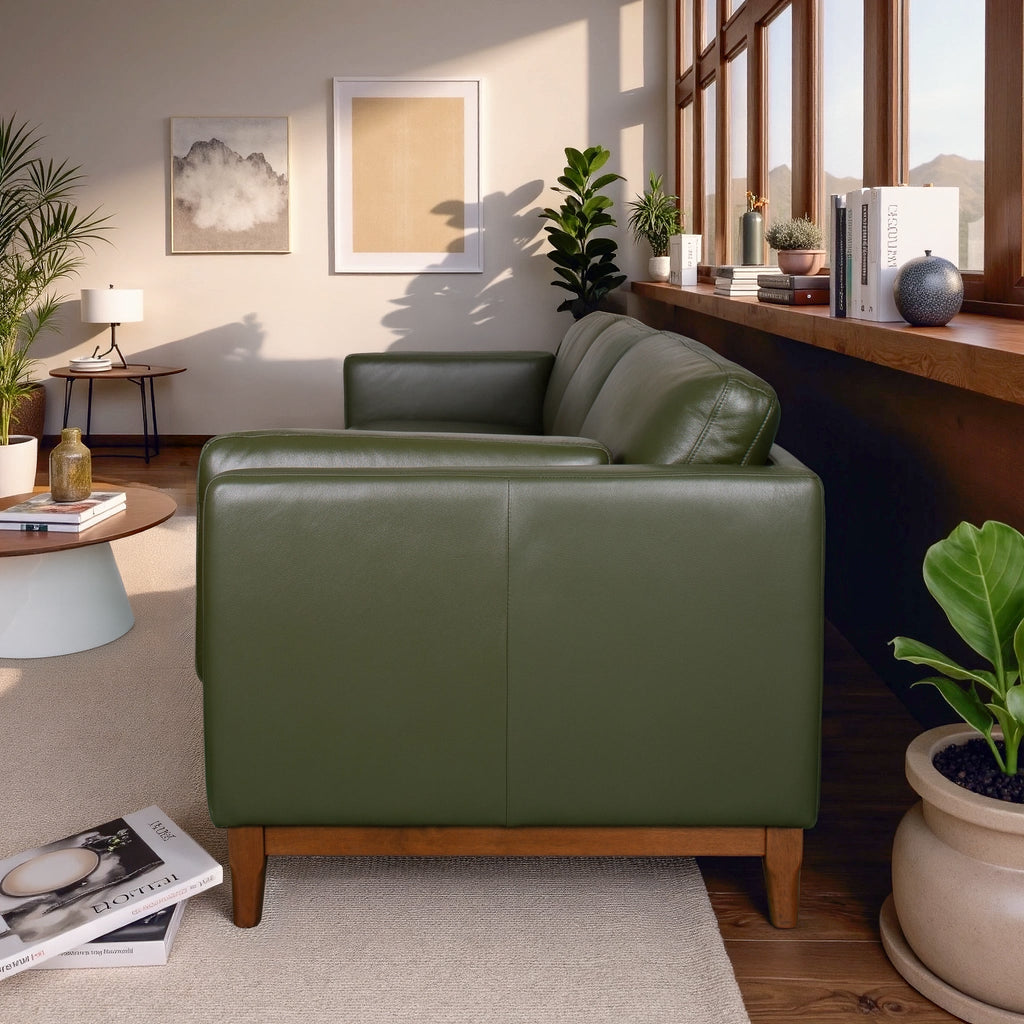 Green leather armchair in a living room with plants and books.