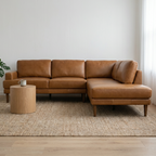 Brown leather sectional sofa in a room with a rug, small table, and plant.