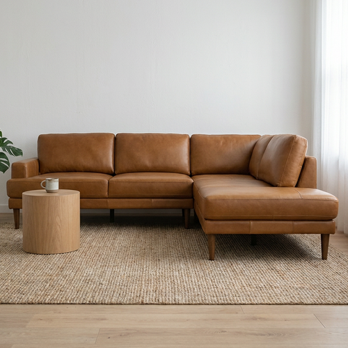 Brown leather sectional sofa in a room with a rug, small table, and plant.